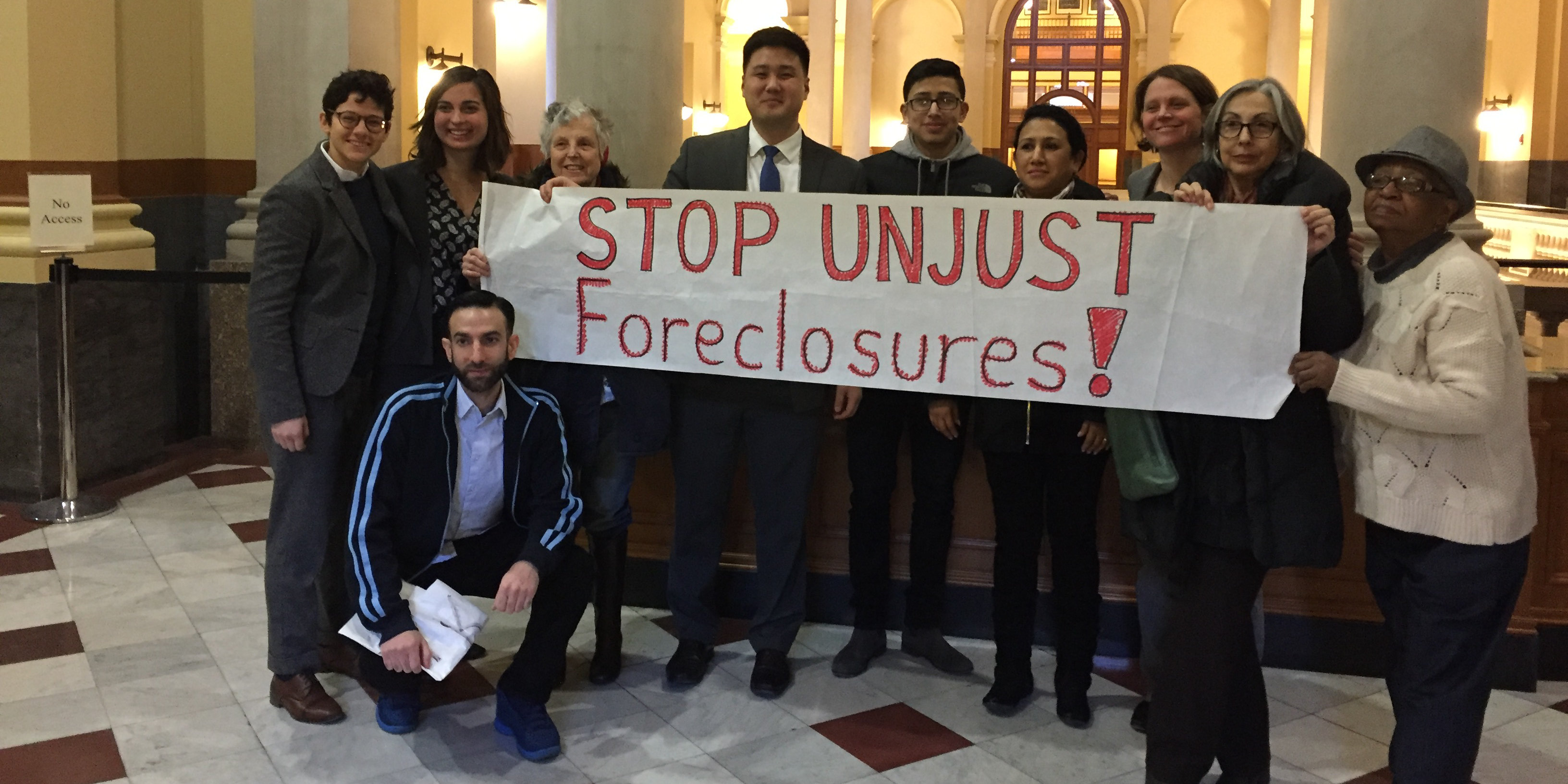 Photo of small group posed holding a banner that says Stop Unjust Foreclosures!